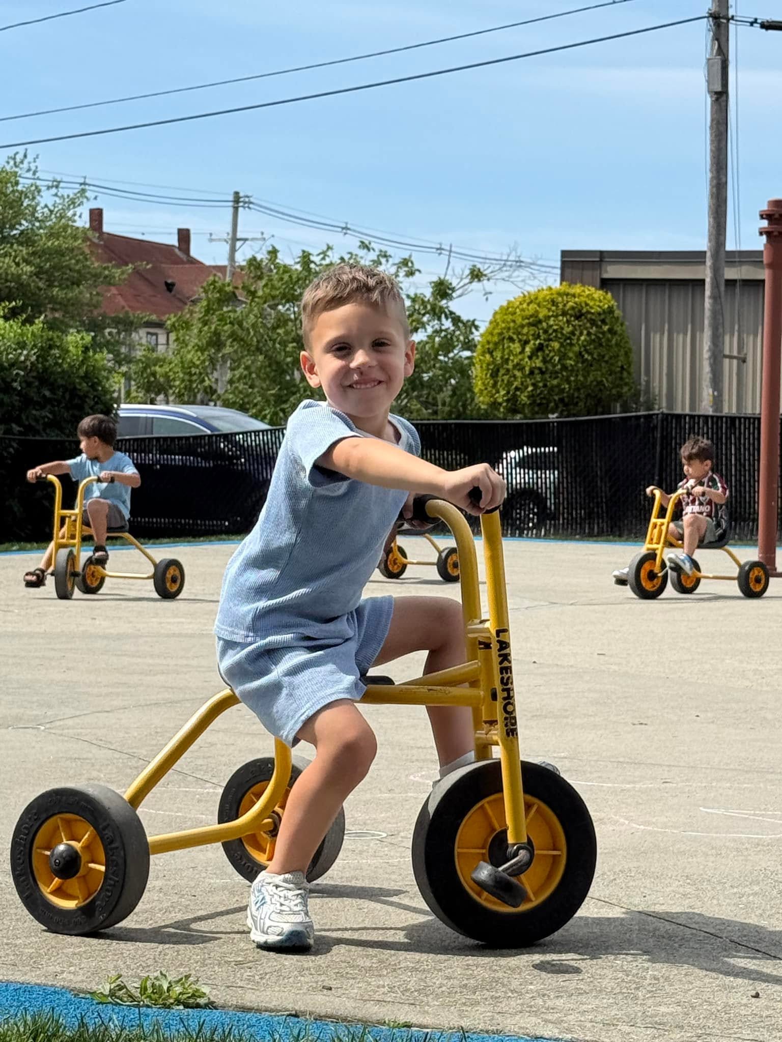 A child riding a tricycle on the Crayon Campus playground