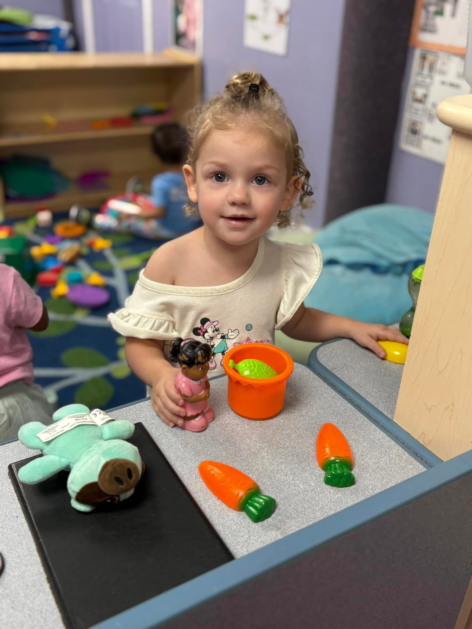 A toddler exploring toy food in a Crayon Campus classroom
